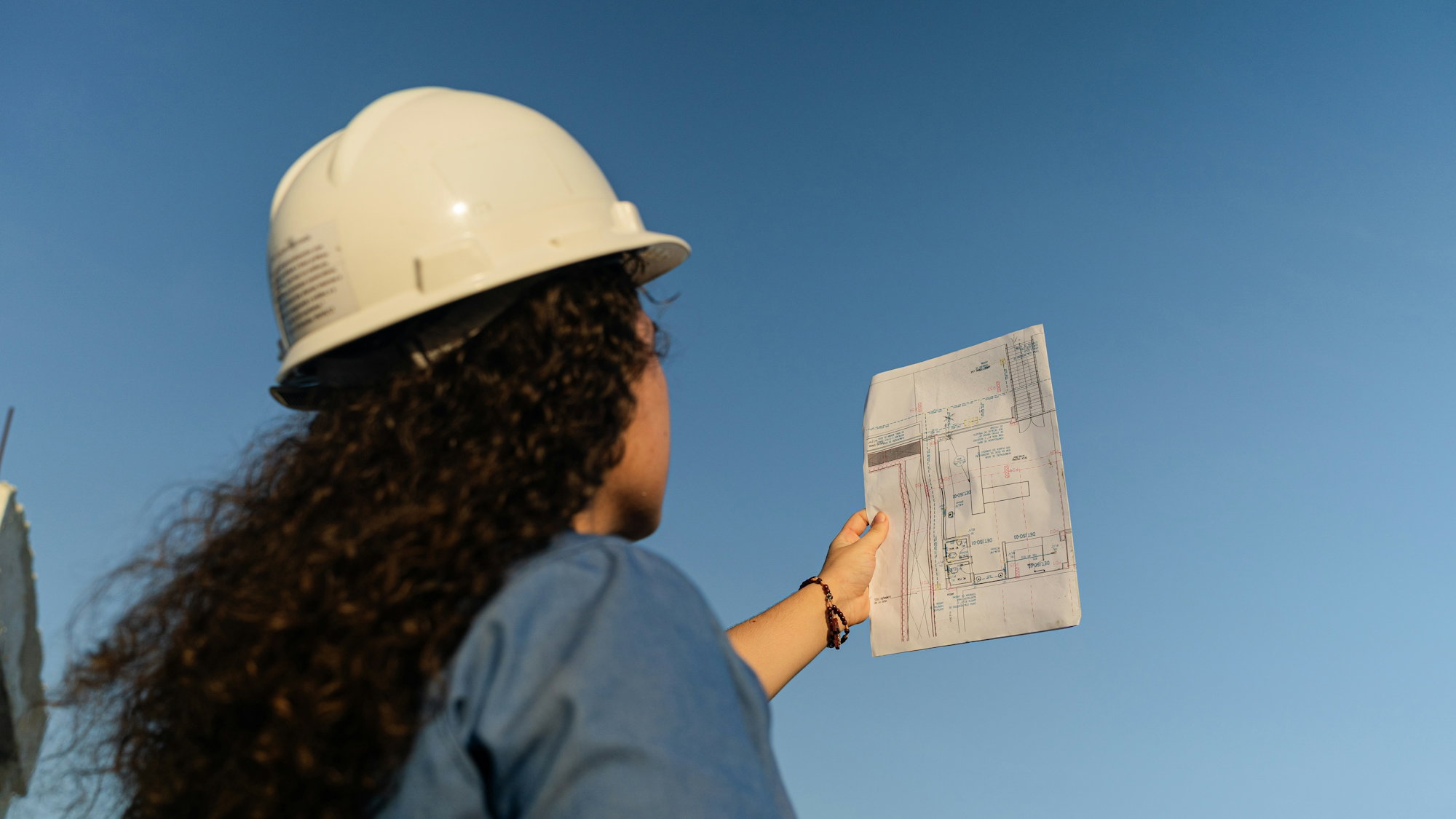 a-woman-wearing-a-hard-hat-holding-a-piece-of-paper.jpg a woman wearing a hard hat holding a piece of paper